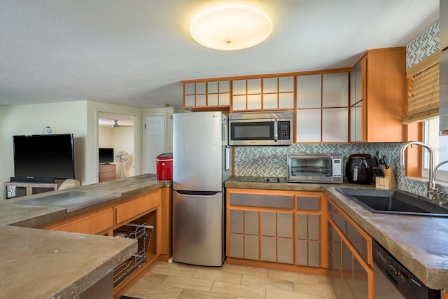 kitchen featuring a toaster, a sink, stainless steel appliances, wood finish floors, and backsplash