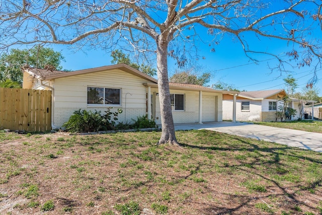 ranch-style house featuring a garage, brick siding, fence, concrete driveway, and a front lawn