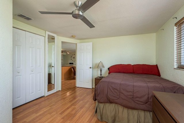 bedroom with light wood-style flooring, a closet, visible vents, and a ceiling fan