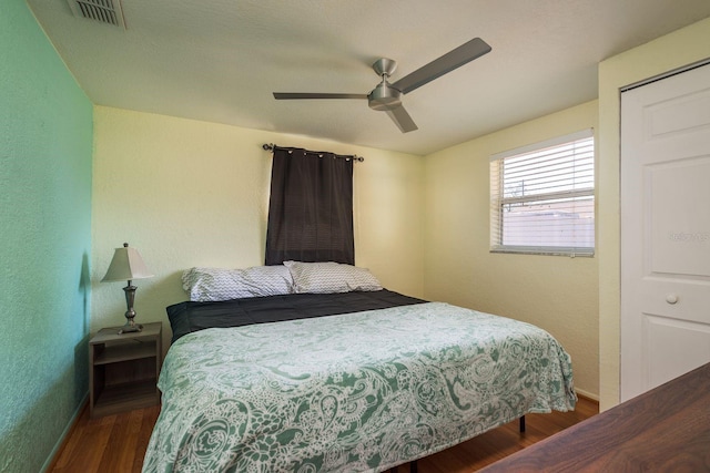 bedroom featuring a textured wall, wood finished floors, visible vents, and a ceiling fan