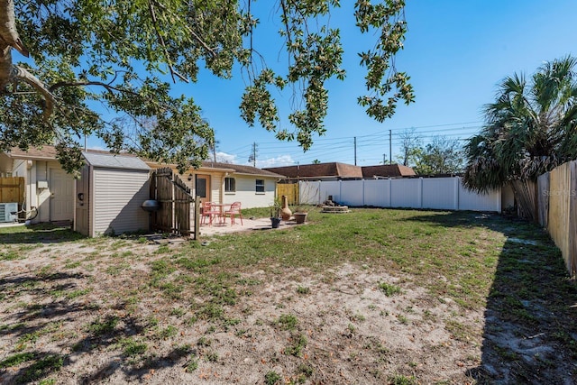 view of yard featuring a patio area, a fenced backyard, a storage unit, and an outbuilding