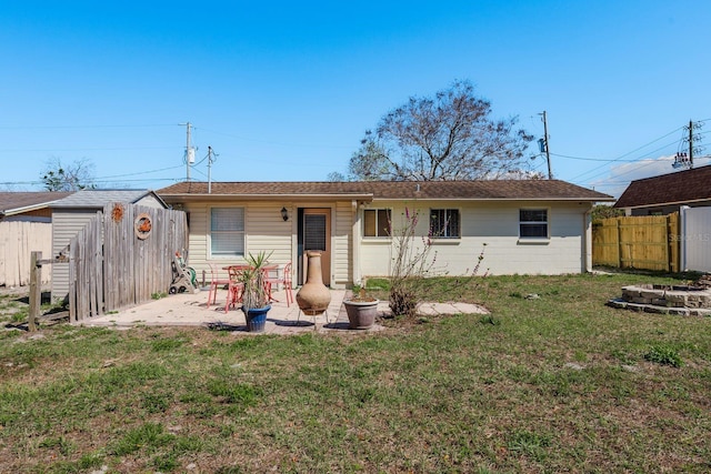 back of property featuring a patio, a lawn, a storage shed, fence, and an outdoor structure