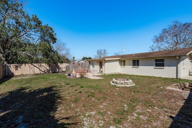 rear view of property featuring an outdoor fire pit, a fenced backyard, and a lawn