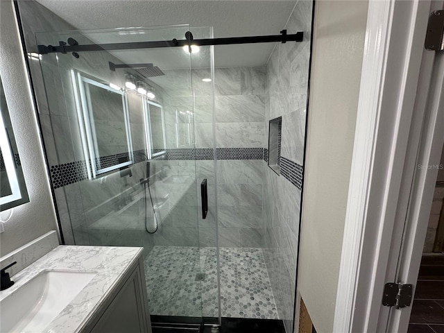 bathroom with a stall shower, vanity, and a textured ceiling