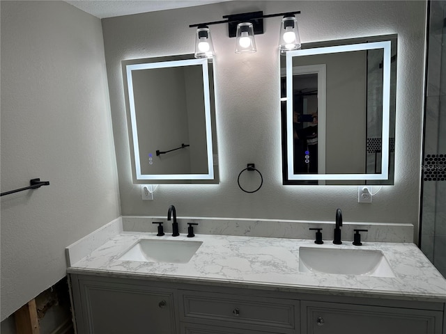bathroom with a textured wall, a sink, and double vanity