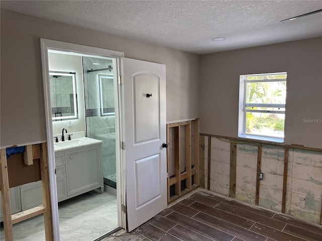 bathroom with wood tiled floor, wainscoting, vanity, and a textured ceiling
