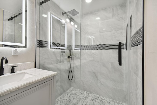 bathroom featuring a stall shower, a textured wall, and vanity