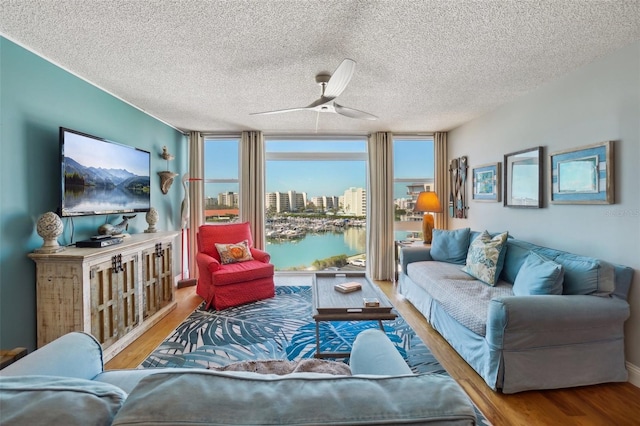 living area featuring expansive windows, a ceiling fan, a wealth of natural light, and wood finished floors