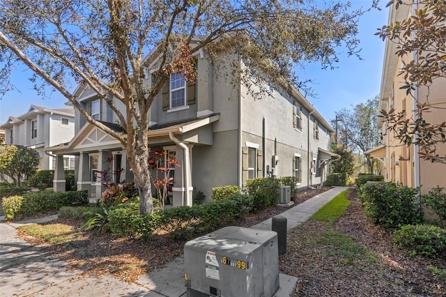 view of property exterior with a porch, a residential view, central air condition unit, and stucco siding