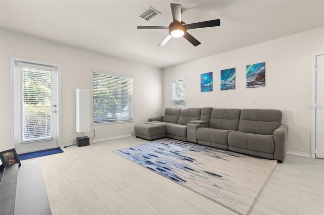 living area featuring baseboards, visible vents, and a ceiling fan