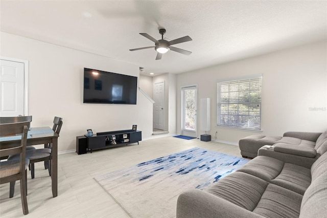 living room featuring a ceiling fan and baseboards