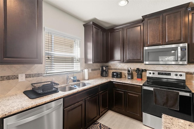 kitchen with tasteful backsplash, dark brown cabinets, stainless steel appliances, and a sink