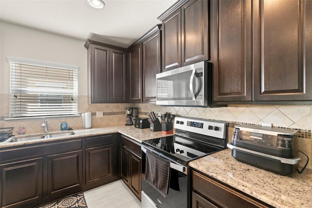 kitchen featuring appliances with stainless steel finishes, a sink, and dark brown cabinetry