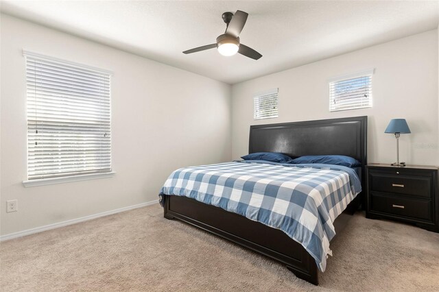 bedroom with a ceiling fan, light carpet, and baseboards