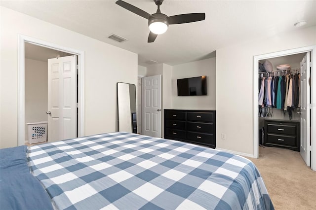 bedroom featuring light carpet, visible vents, a ceiling fan, a closet, and a walk in closet