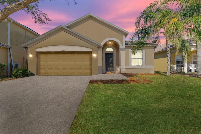 view of front of home with a front yard, driveway, an attached garage, and stucco siding