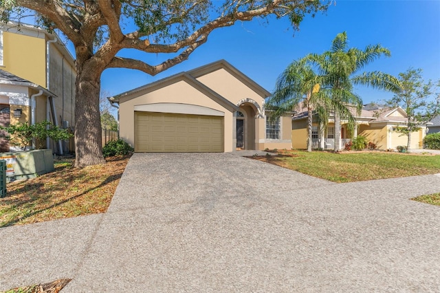 view of front of home featuring a garage, driveway, a front yard, and stucco siding