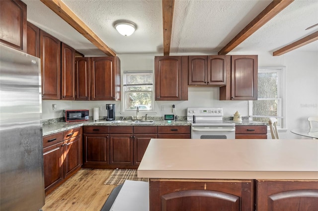 kitchen featuring stainless steel refrigerator, beamed ceiling, light countertops, a textured ceiling, and white electric range