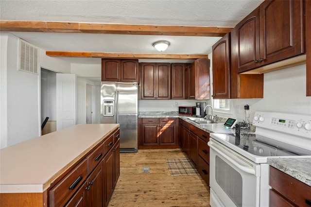 kitchen featuring beam ceiling, white range with electric cooktop, visible vents, a sink, and stainless steel fridge