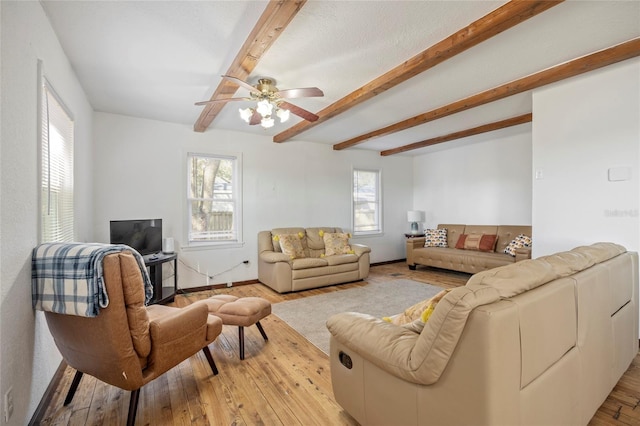 living room featuring baseboards, beamed ceiling, and light wood finished floors