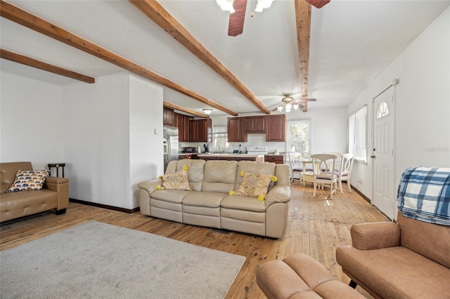 living area with baseboards, beamed ceiling, light wood finished floors, and ceiling fan