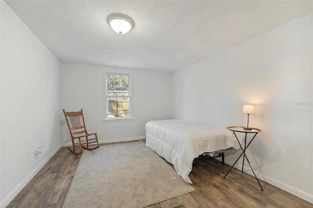 bedroom featuring a textured ceiling, wood finished floors, and baseboards