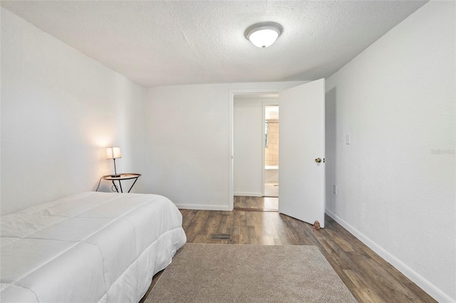 bedroom featuring a textured ceiling, wood finished floors, and baseboards