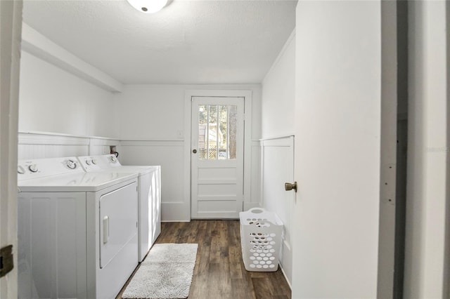 laundry room featuring dark wood-style flooring, a wainscoted wall, washing machine and dryer, a textured ceiling, and laundry area