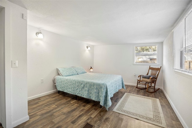 bedroom featuring a textured ceiling, baseboards, and wood finished floors