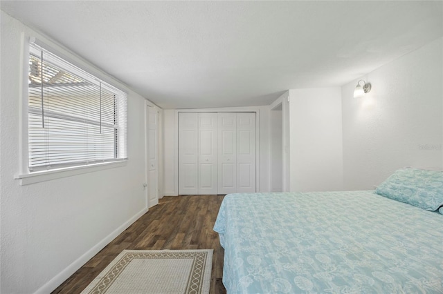 bedroom with baseboards, dark wood finished floors, and a closet