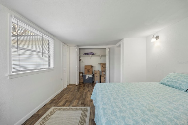 bedroom with dark wood-type flooring, a closet, and baseboards