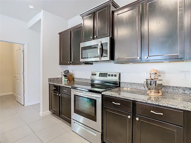 kitchen featuring appliances with stainless steel finishes, dark brown cabinets, light stone counters, and light tile patterned flooring