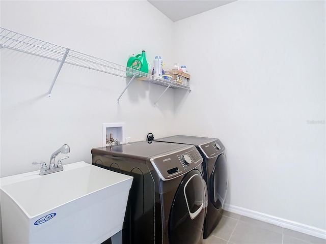 laundry area with light tile patterned floors, laundry area, a sink, baseboards, and washing machine and clothes dryer