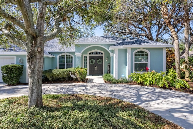 ranch-style home with driveway, roof with shingles, a garage, and stucco siding