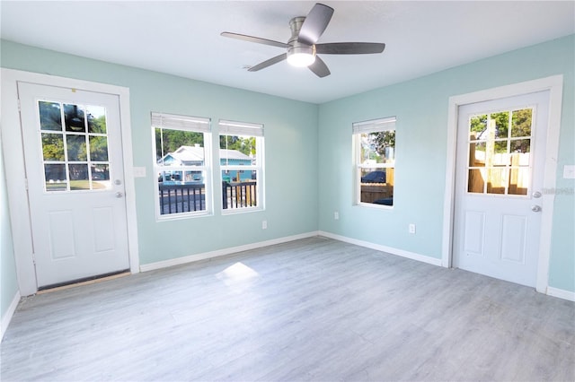 interior space with a ceiling fan, baseboards, a wealth of natural light, and wood finished floors