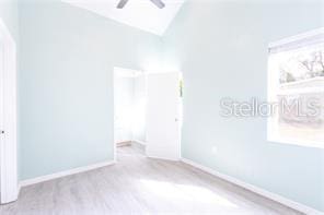 unfurnished bedroom featuring high vaulted ceiling, wood finished floors, a ceiling fan, and baseboards