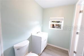 bathroom with wood finished floors, toilet, and baseboards