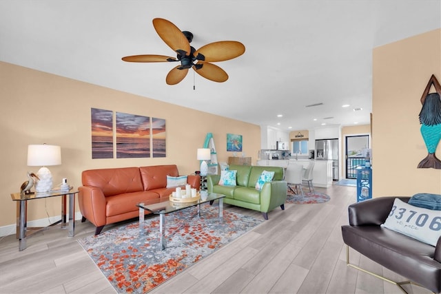 living room featuring baseboards, recessed lighting, a ceiling fan, and light wood-style floors