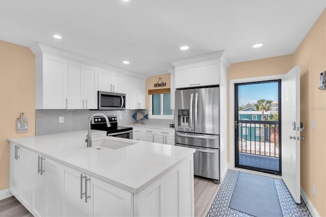 kitchen with appliances with stainless steel finishes, light countertops, a peninsula, and tasteful backsplash