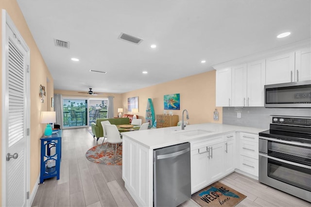 kitchen featuring a sink, open floor plan, appliances with stainless steel finishes, backsplash, and wood tiled floor