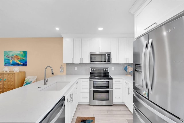 kitchen featuring a peninsula, stainless steel appliances, a sink, and light countertops