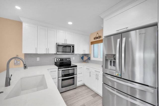 kitchen with light countertops, appliances with stainless steel finishes, a sink, and tasteful backsplash