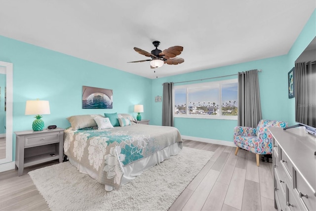 bedroom featuring light wood-style floors, baseboards, and a ceiling fan