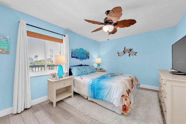 bedroom with light wood-style flooring, a ceiling fan, and baseboards