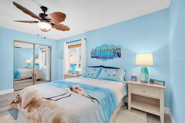 bedroom with light wood-style flooring, baseboards, ceiling fan, and a closet