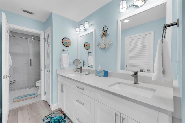 bathroom featuring a sink, visible vents, a closet, double vanity, and a stall shower