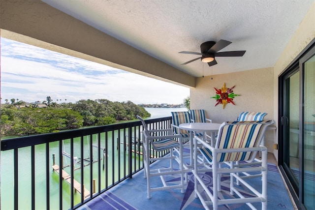 balcony featuring a water view and a ceiling fan