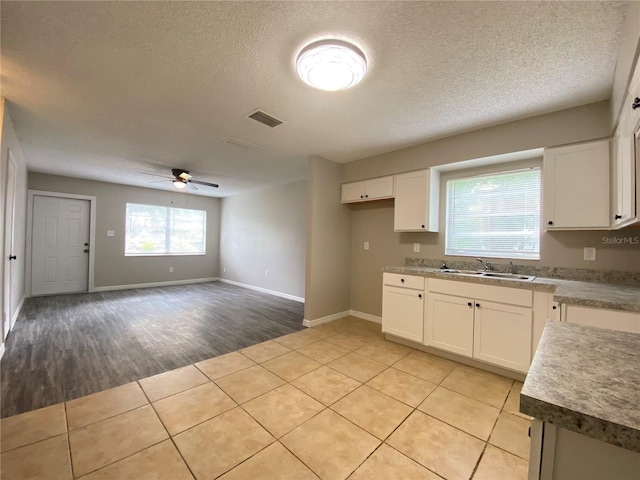 kitchen with visible vents, white cabinets, a sink, and light tile patterned flooring