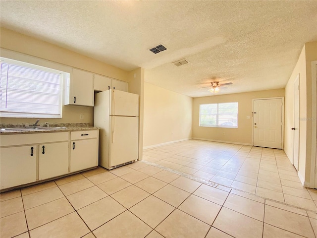 kitchen featuring light tile patterned floors, visible vents, a ceiling fan, freestanding refrigerator, and a sink