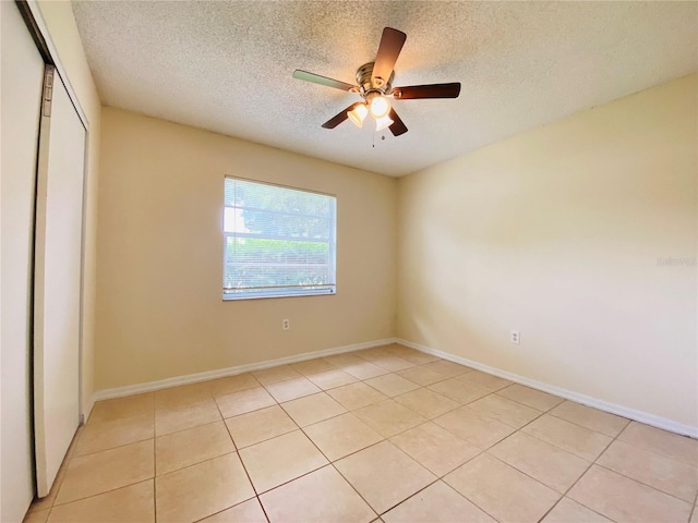 unfurnished room featuring ceiling fan, a textured ceiling, light tile patterned flooring, and baseboards